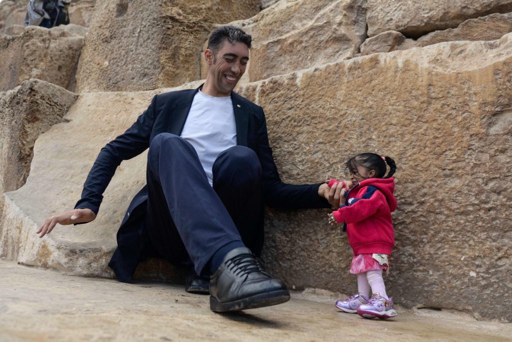India's Jyoti Amge (R), the world's shortest woman poses for a picture with Sultan Kosen of Turkey, the world's tallest man, at the foot of one of the three Pyramids of Giza in Egypt on January 26, 2018. / AFP PHOTO / STRINGER